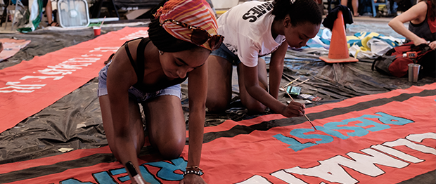 Two volunteers painting a banner for a climate march.